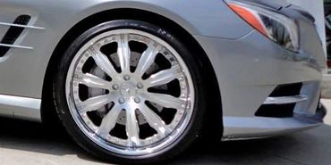 Silver sports car with shiny custom wheels parked outside Butler Tires & Wheels.