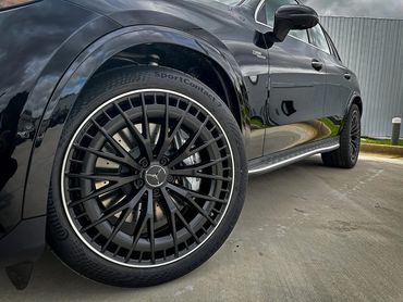 Close-up of a black Mercedes-Benz AMG wheel on a sleek black car.