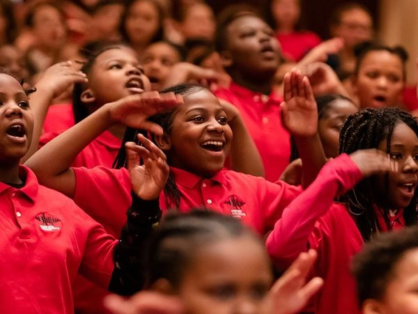 Children in red shirts singing and enjoying.