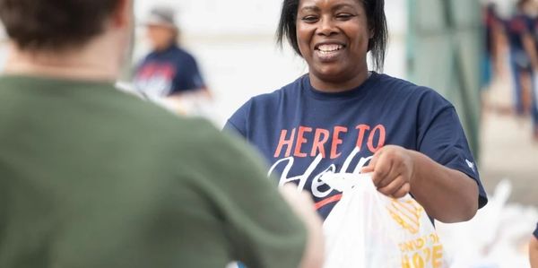 Woman happily handing over a bag of groceries.