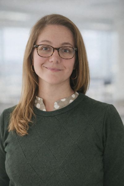 Smiling woman with glasses in a green sweater.