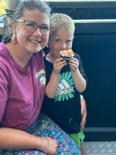 Woman and child smiling with a cupcake.
