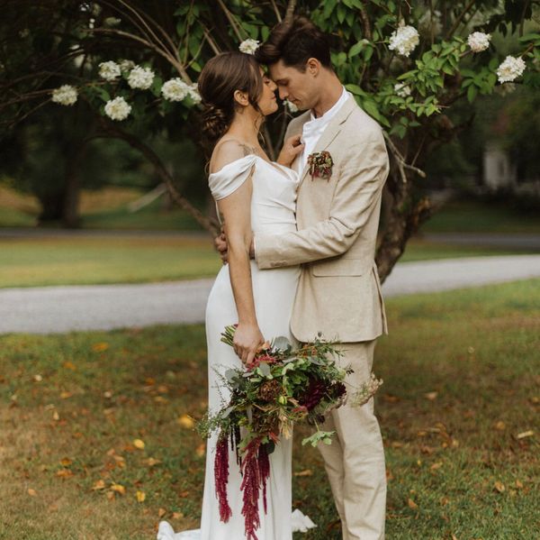 Bride and groom embracing under a flowering tree.