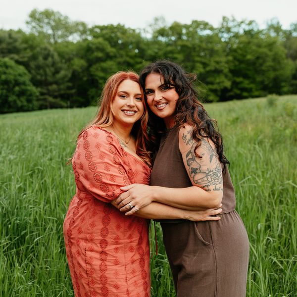 Two women hugging in a green field.