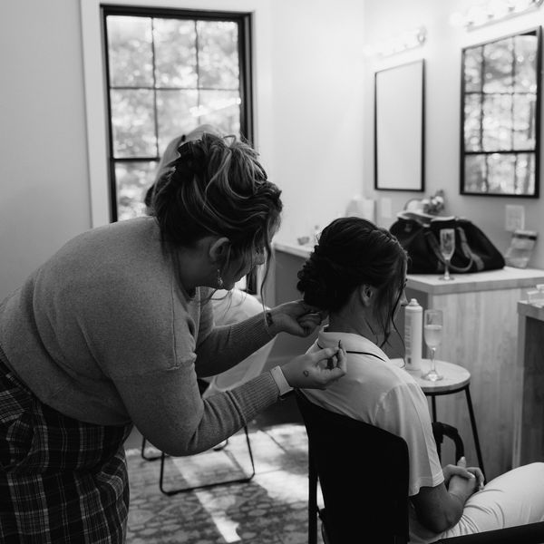 Person styling another person's hair indoors.