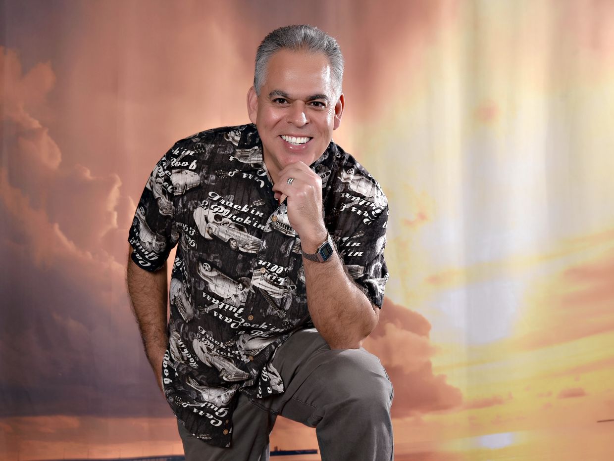 Man smiling and posing with hand on chin.