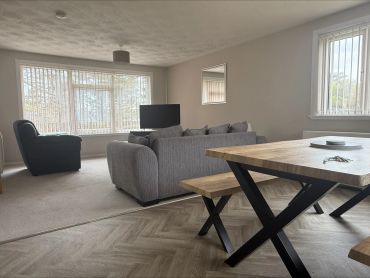 Modern living room with gray sofas and wooden dining table.