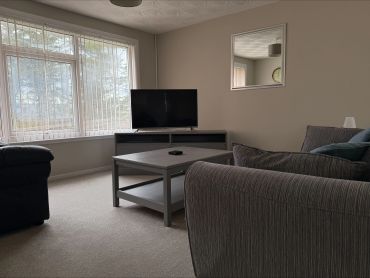 Cozy living room with gray sofas, a TV on a stand, and a large window letting in natural light.