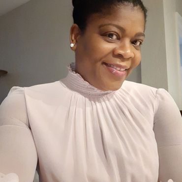 Smiling woman in a light pink high-neck blouse.