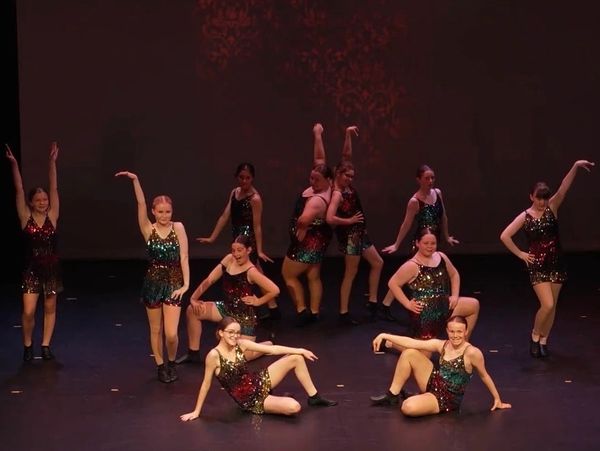 A group of dancers performing on stage in sparkly outfits.