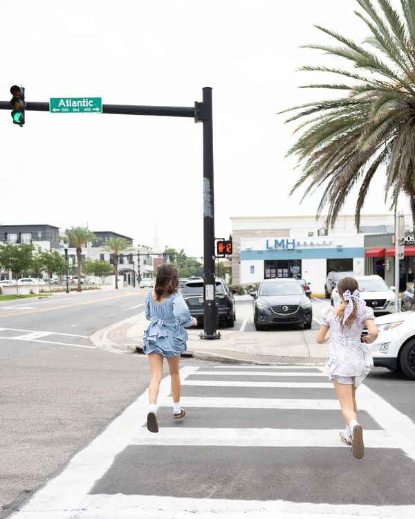 Two girls in dresses running across a crosswalk on Atlantic Boulevard.