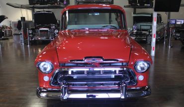 Front view of a classic red car in a showroom.