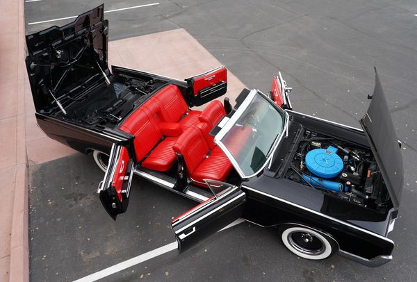 Classic black convertible car with all doors, hood, and trunk open.