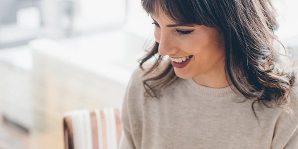 A woman smiling warmly while looking down.