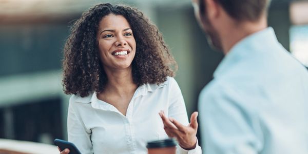 Two colleagues having a friendly conversation in an office setting.