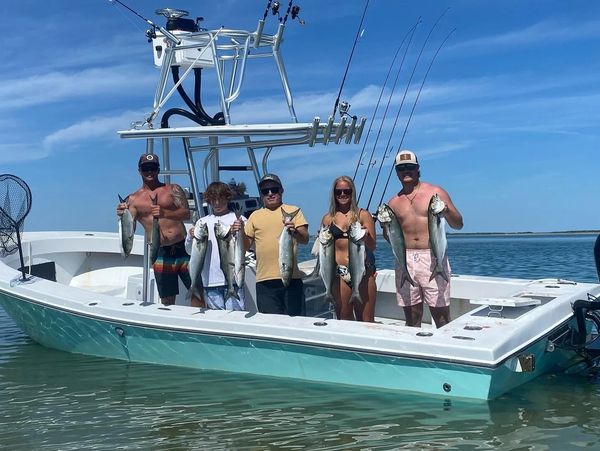 Group holding fish on a boat in clear waters.