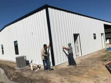 Two employees working on constructing a metal building.