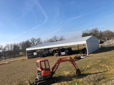 Construction equipment in front of a large metal building.