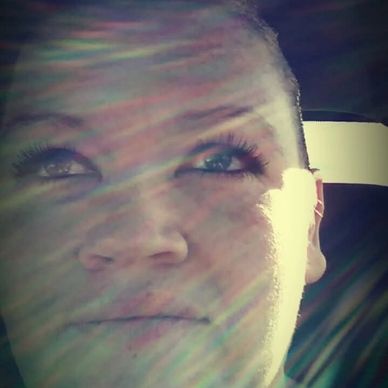 Close-up of a person's face with sunlight rays creating a lens flare effect.