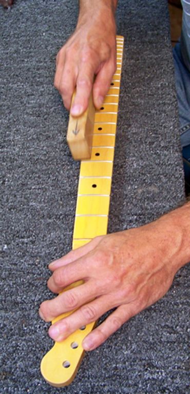 Person polishing a guitar neck.