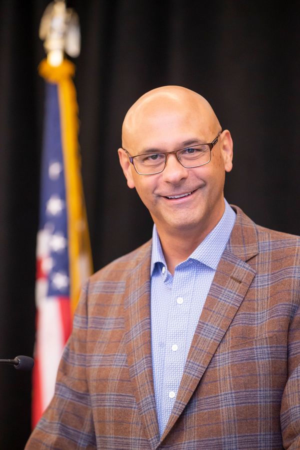 Man smiling in front of American flag.