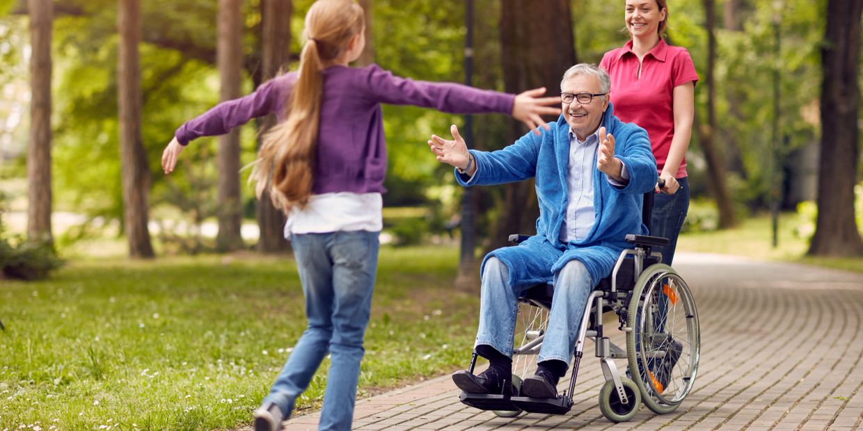a kid in a purple jacket running to embrace an elderly on a wheelchair