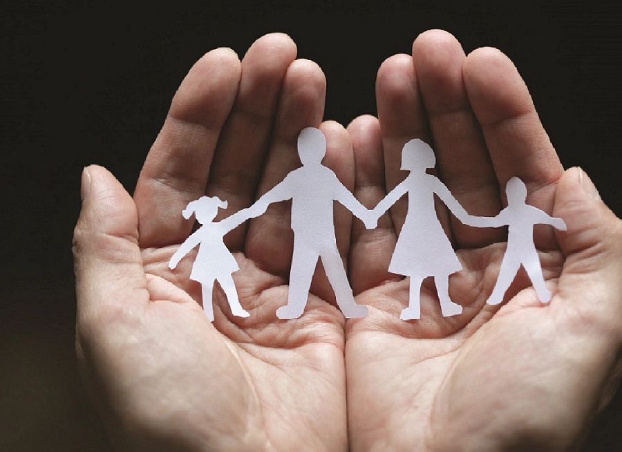 Hands holding paper cutout family figures.