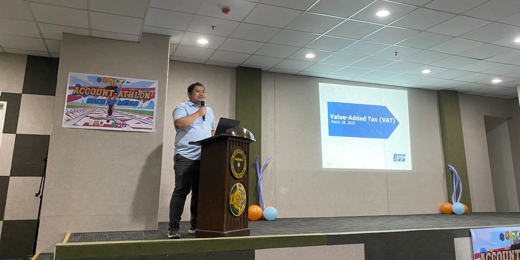Speaker presenting on Value-Added Tax at an event.