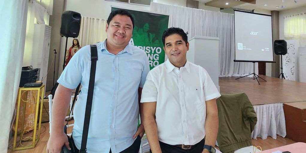 Two men posing and smiling indoors at an event.