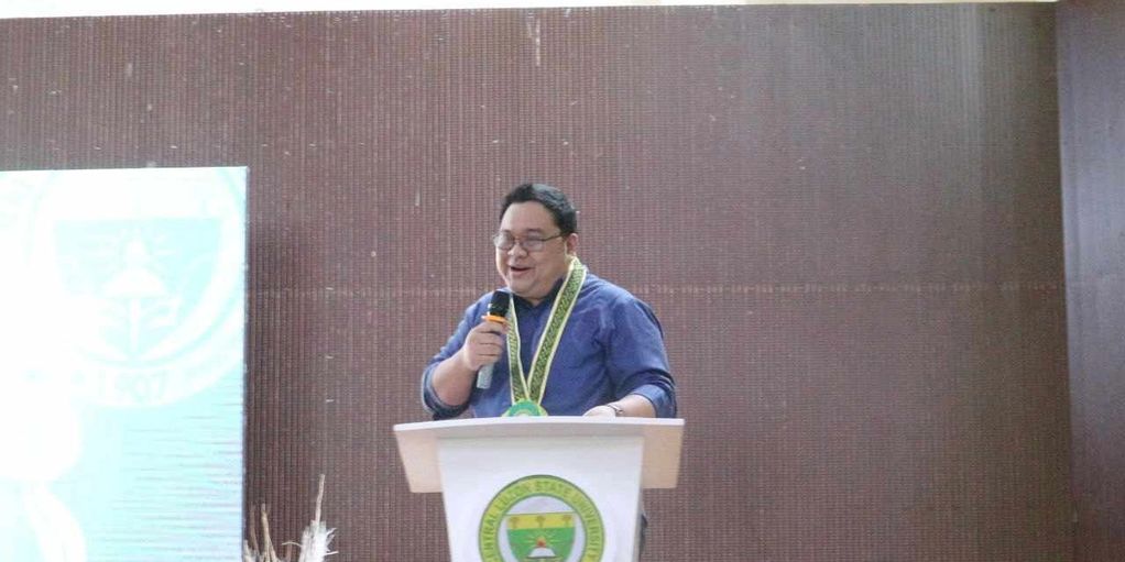 Man speaking at podium with microphone and medal.
