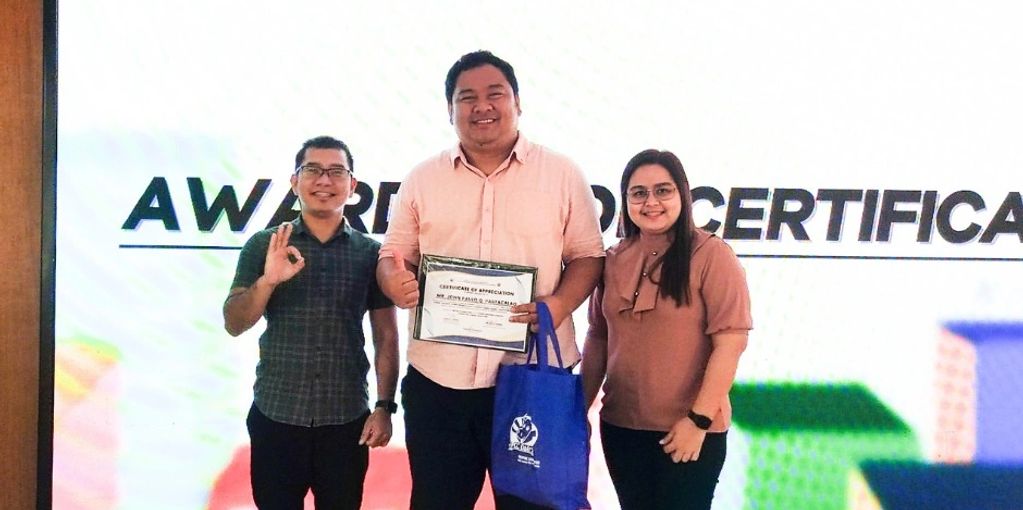 Three people at an award ceremony, one holding a certificate.