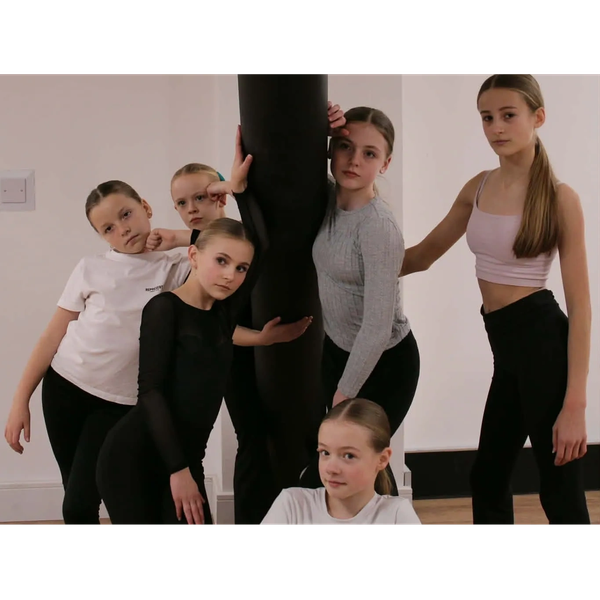 Group of young dancers posing together indoors.
