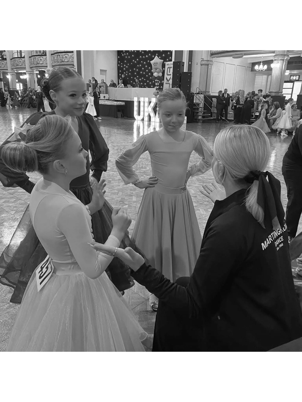 Young girls in colorful dresses at a dance event.