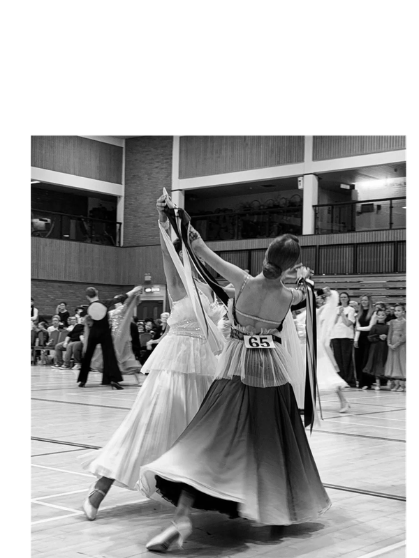 Black and white image of ballroom dancers competing indoors.