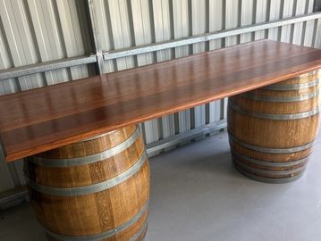 Wooden table supported by two barrels in a metal shed.