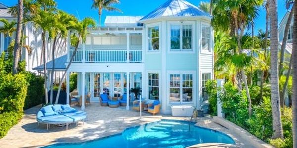 Beautiful white two-story house with a pool and palm trees.