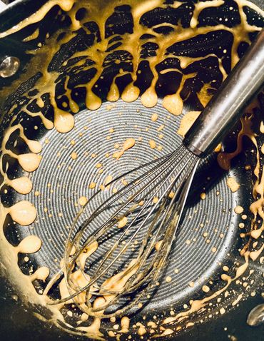 Melted honeycomb dregs and whisk inside saucepan after cooking