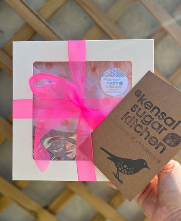 Gift box with pink ribbon. Hand holding a card in front of it
