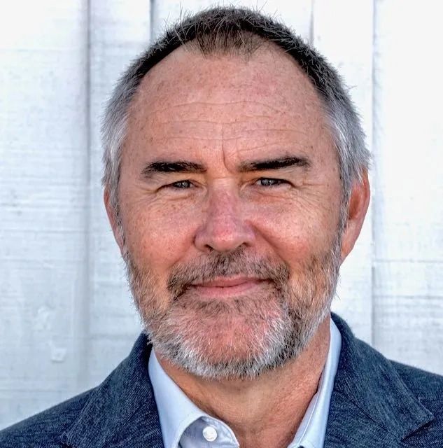 Smiling middle-aged man with gray hair and beard.