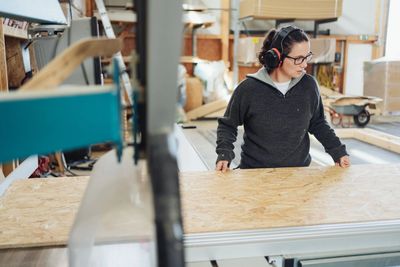Worker cutting board panels in a fabrication workshop