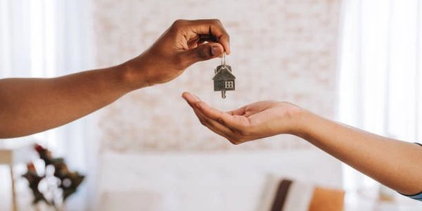 Handing over a house key symbolizing home ownership or rental.