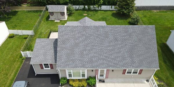 A suburban house with a gray roof and green lawn.