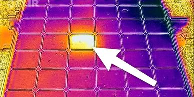 Thermal image of a solar panel with a hot spot highlighted by an arrow.