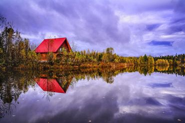 Paysage d'automne au bord d'un lac avec un chalet au toit rouge au bord d'un lac miroir - reflet