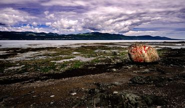 Paysage de l'isle-aux-Coudres avec un graffiti sur un rocher. vue sur le fleuve et Baie St-Paul