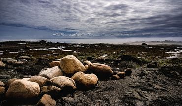vue sur le fleuve avec en avant plan des roches - Le ciel est nuageux