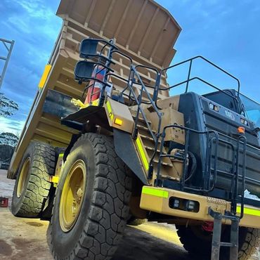 Large CAT mining dump truck with raised bed at dusk.