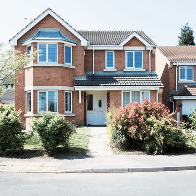 Two-story brick house with tiled roof and front garden.