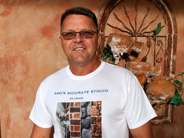 Man wearing glasses and a white t-shirt with stucco designs.