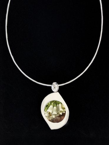A silver pendant on chain with art inserted